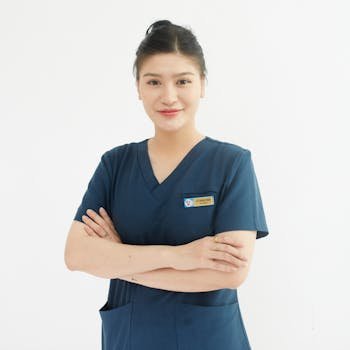 Professional portrait of a smiling female nurse with folded arms in a medical uniform.
